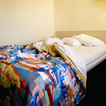 Interior shot of motel room with messy unmade bed.