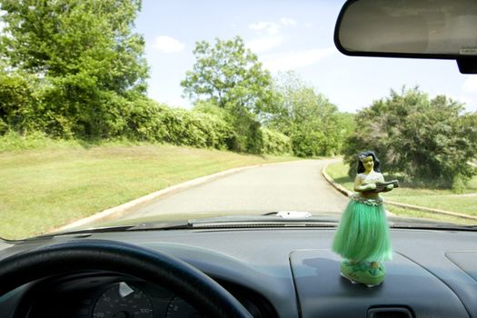 Hula girl on dashboard of car interior.