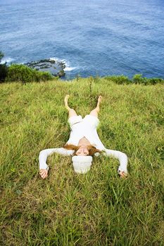 Young woman relaxing in grass near ocean in Maui, Hawaii.