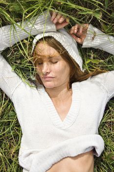 Portrait of attractive young redheaded woman lying in grass resting.