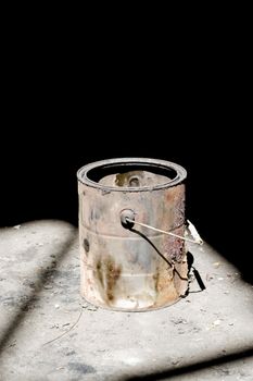 Still life shot of a rusty old paint bucket under dramatic lighting.