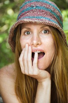 Portrait of pretty redhead with surprised expression on her face wearing hat.