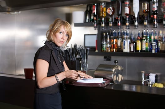 Attractive blond business woman standing in a bar with her notebook