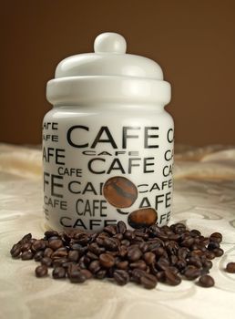 Ceramic jar and coffee baens on tablecloth