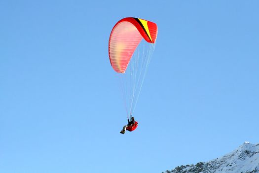 Paraglider flying high over the mountains in winter
