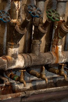 Old rusty pipes and valves in cellar of old house