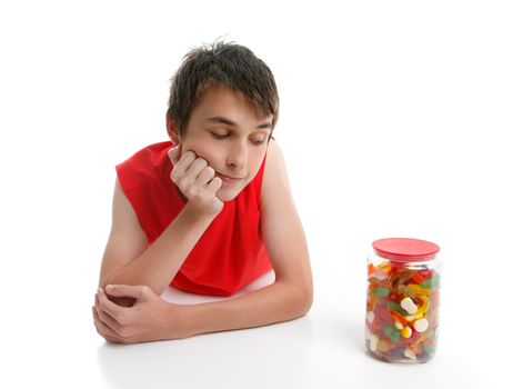 A boy ponders whether to open a jar of assorted confectionery.  White background.