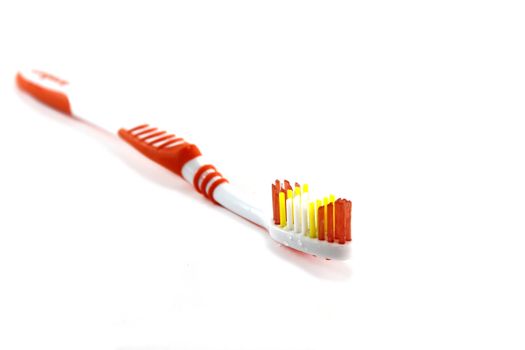 Close up of a orange toothbrush over white background