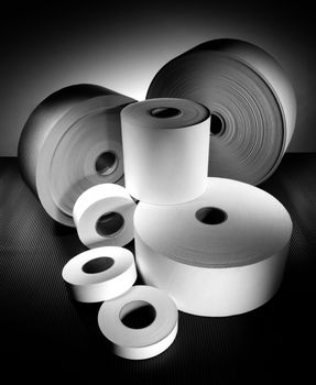 rolls of different sized paper on dark background in black and white