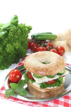 Bagel with Camembert cheese, tomato, cucumber, cream cheese and lettuce on white background