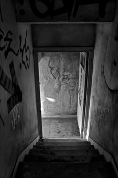 Stairs and exit door of abandoned house. Black and white.