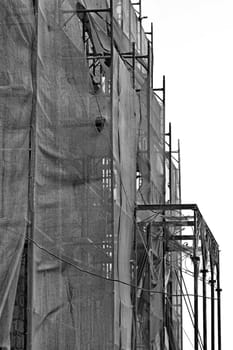 Abandoned mansion covered with torn debris netting. Black and white.