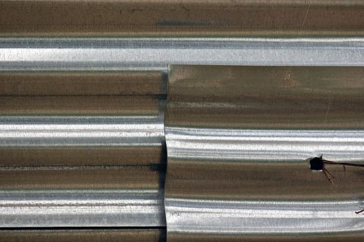 Layers of corrugated aluminum sheeting fence tied with rusty wire.