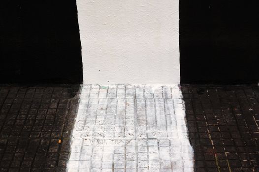 Wall and sidewalk painted black and white. Urban background.
