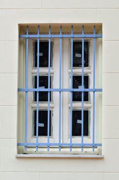 Protective metal bars and dirty window of a renovated building.