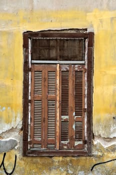 Boarded up window shutters and grungy yellow wall. Abandoned house detail.