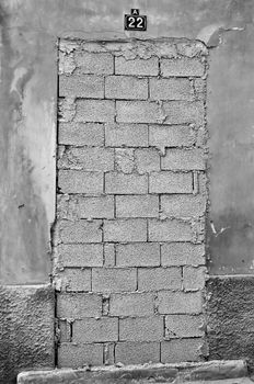 Bricked up door and weathered wall of an abandoned building. Black and white.