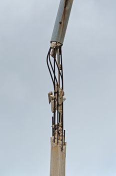 Broken concrete pole and rusty steel bars. Industrial detail.