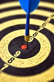 Dartboard target and blue dart arrow. Selective focus.