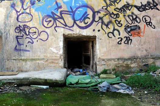 Dirty mattress and wooden pillow next to an abandoned house basement door.