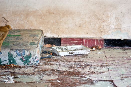 Dusty mattress and blanket on the tilled floor of an abandoned house.