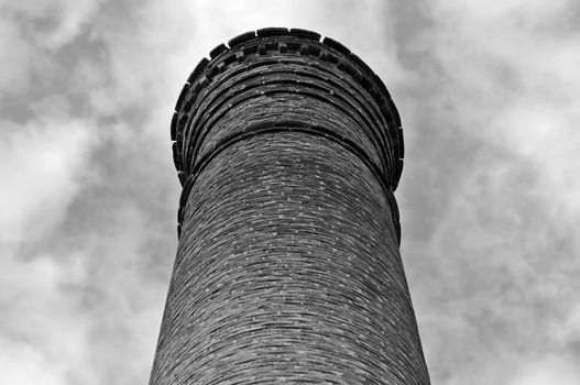 Weathered brick chimney of an abandoned factory. Black and white.
