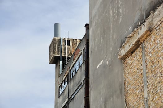 Abandoned factory exterior and crumbling wall. Industrial building.