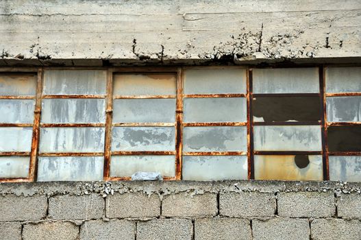 Old factory cinder block wall and broken windows.