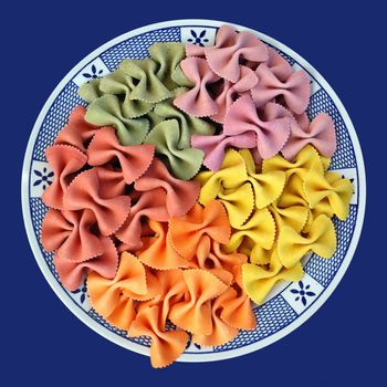 Plate with colored flavors of italian farfalle pasta. Creative food.