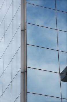 Sky mirrored on the windows of a modern glass building. Architectural detail.
