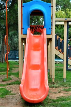 Red plastic slide at a kids playground.
