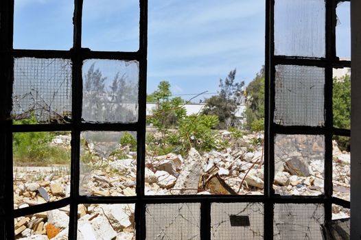 View to a pile of rubble from the broken windows of a partially demolished factory.