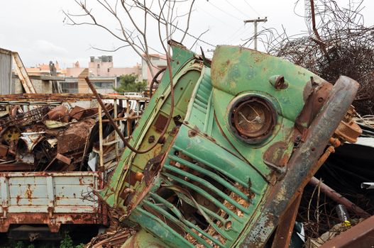 Rusty vintage car and scrap metal at a junkyard.