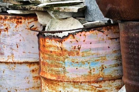 Rusty metal barrels filled with rocks. Abstract background.