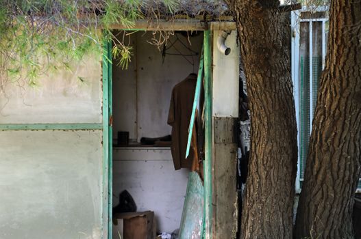 Broken door of an abandoned house and hanging shirt.