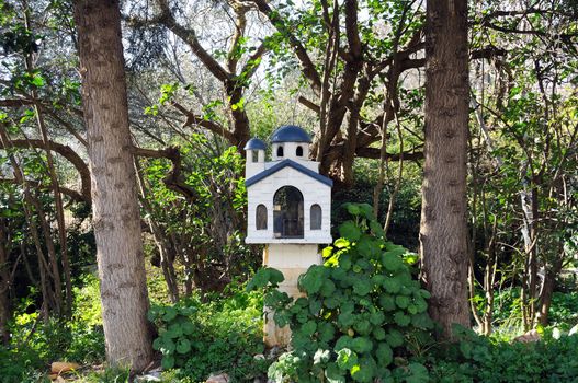 Small street church shrine surrounded by trees and plants. Athens, Greece.