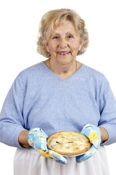 Welcome home concept: grandma is smiling while offering warm homecooked meat pie, wearing oven mits.