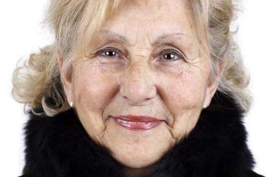 Portrait of friendly sympathetic senior woman smiling looking at camera with black fur collar; great details showing all signs of aging.