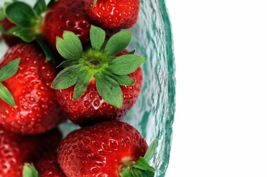 Glass bowl with fresh strawberries on white background. Selective focus macro.