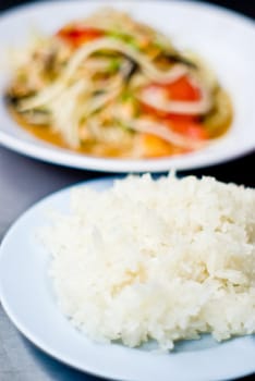 Sticky rice in the blue dish with green papaya salad background