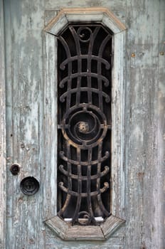 Weathered wooden door with peeling paint and vintage metalwork pattern.