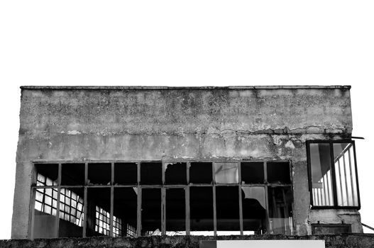 Broken windows facade of an abandoned warehouse. Black and white.