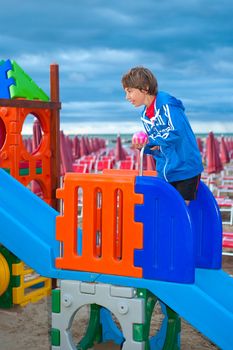 a boy on the children's playground at the beach