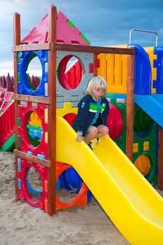 a blond boy is playing in the children's playground