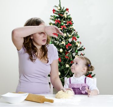 little girl and mother are preparing Christmas cookies, Mom seems to be tired