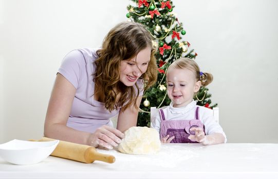 little girl and mother are preparing Christmas cookies