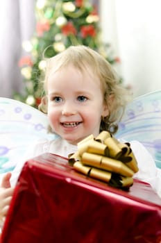 little girl smiling with christmas gift in hand