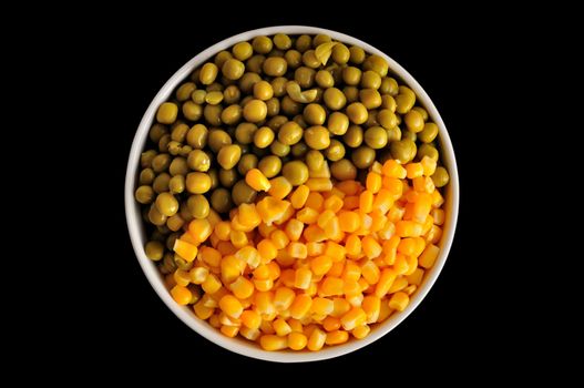 a plate with corn and peas, isolated, on a black background