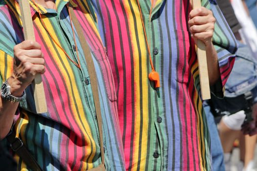 Couple of lesbians hugging and wearing identical rainbow shirts, whistles and sticks of flags at the Gay Pride