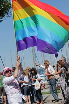 Man holding a big rainbow flag while taking part in Gay Pride Parade, Geneva, Switzerland.